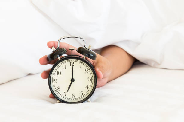 istock Man extend hand reaching to turn off alarm clock switch 1142558763