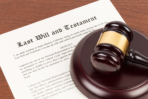 Last will and testament on yellowish paper with wooden judge gavel; document is mock-up