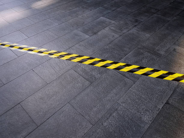 istock Yellow Black Safety Warning Tape on Tiled Floor Covering Electrical Cable Underneath 1142561868