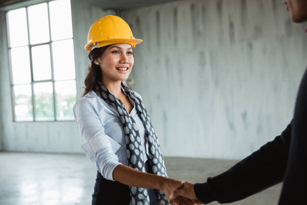 istock businesswoman with hardhat shaking hand 1142565388