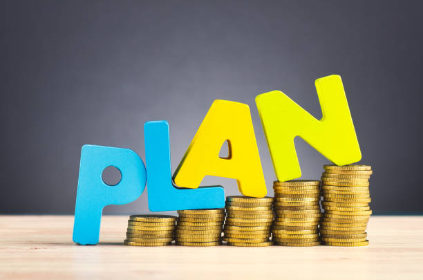 financial planning concept,word PLAN and stacking coins on wooden desk over beautiful reverberation gradient background