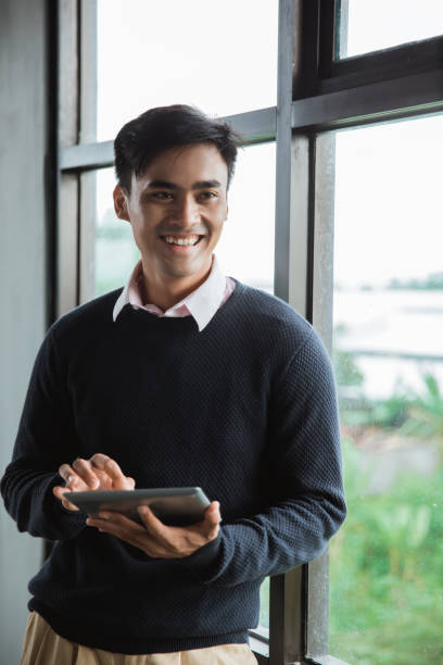 istock a businessman holding digital tablet look at the camera in front the windows 1142570667