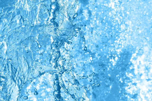 Photo of Water spray and splash, blue background. Water droplet