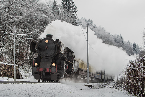 A German war locomotive, kriegslok, is hauling a Christmas oldtimer train. The engine is decorated with christmas lights.