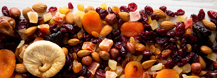 Dried fruits and nut mix on a white wooden surface, top view. Overhead, from above, flat lay.