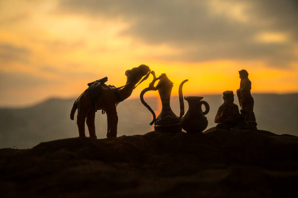 Camel caravan going through the sand dunes in the desert at sunset. Eastern travel concept. Artwork decoration