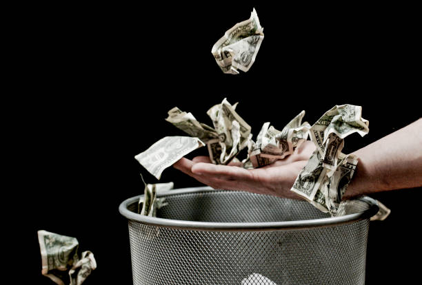 istock View of crushed money falling on human hand above bin 1142578461