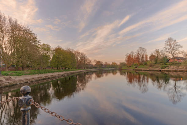 The River Ouse at dawn. The River Ouse flowing downstream through the city of York.  Trees line the river bank and there is a blue sky with clouds above. ouse river photos stock pictures, royalty-free photos & images