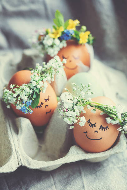 Natural easter eggs with funny painted face and sweet flower wreath