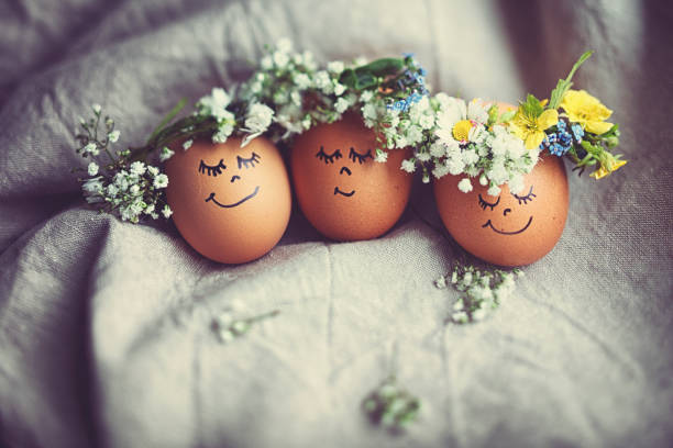Natural easter eggs with funny painted face and sweet flower wreath