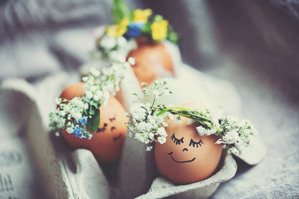 Natural easter eggs with funny painted face and sweet flower wreath