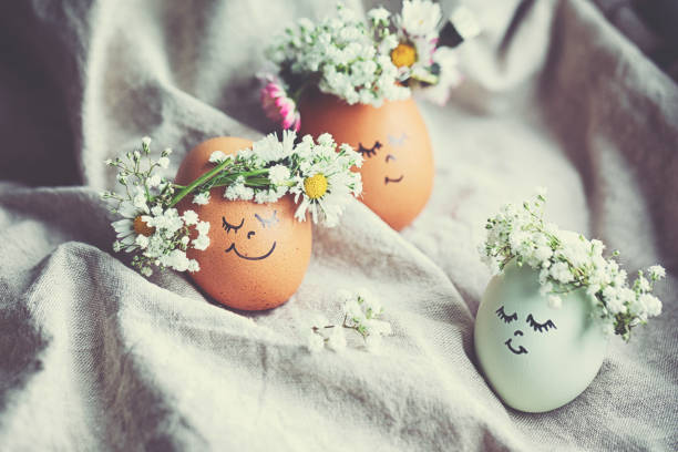 istock Natural easter eggs with funny painted face and sweet flower wreath 1142584695