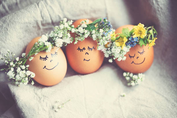 istock Natural easter eggs with funny painted face and sweet flower wreath 1142584803