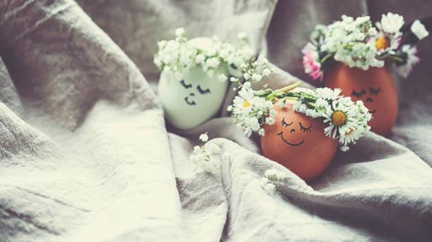 istock Natural easter eggs with funny painted face and sweet flower wreath 1142584896
