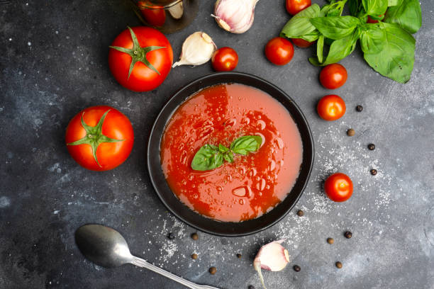 Gazpacho cold summer vegetarian tomato soup with basil in a bowl Gazpacho cold summer vegetarian tomato soup with basil in a bowl on black stone background. Summer soup concept tomato soup stock pictures, royalty-free photos & images