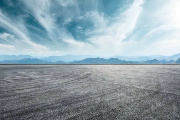 Empty asphalt race track and mountain with clouds background