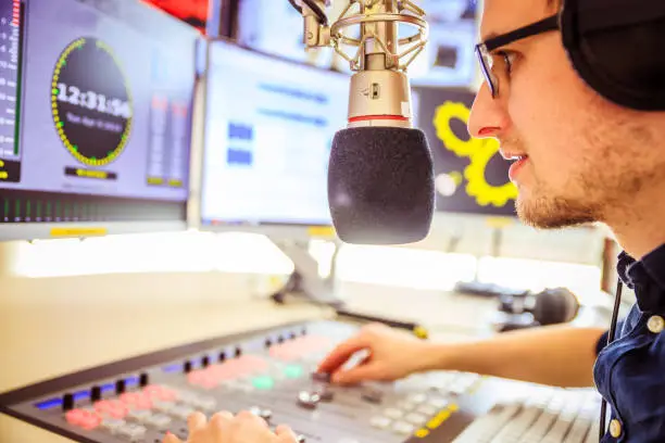 Young man in the broadcasting studio, radio, talking into the microphone