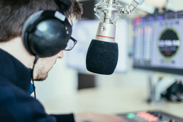 istock Radio moderator is sitting in a modern broadcasting studio and talking into the microphone 1142589946