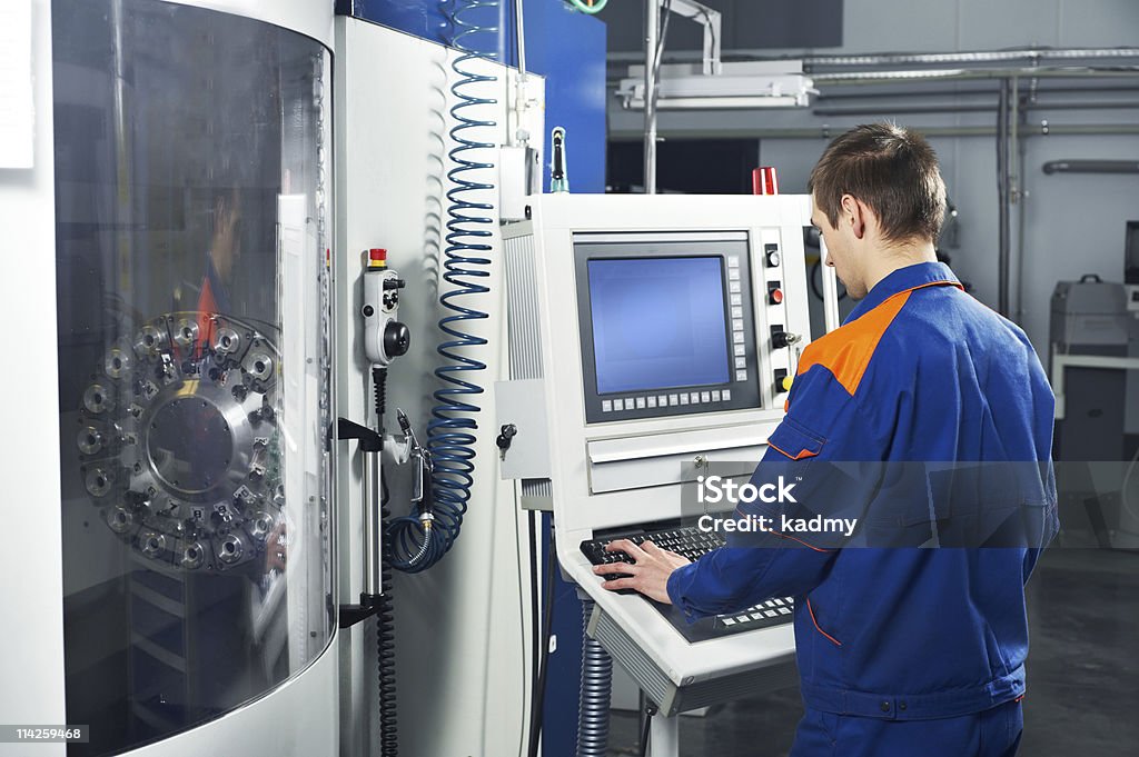 Worker performing a job at tool workshop mechanical technician near cnc milling machine center at tool workshop Machinery Stock Photo