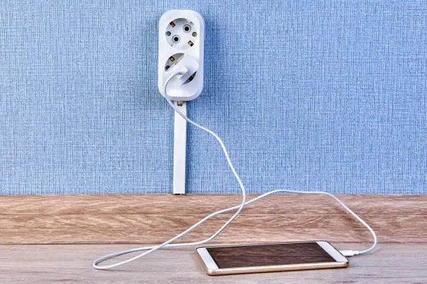 Smartphone is plugged into the charger which is inserted into a double outlet.