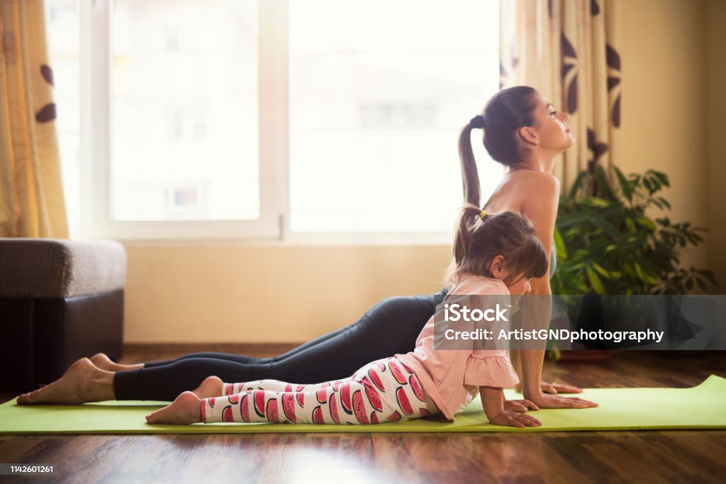 You're doing it like mommy now, Full length shot of a mother and daughter doing yoga together Full length shot of a mother and daughter doing yoga together Child Stock Photo