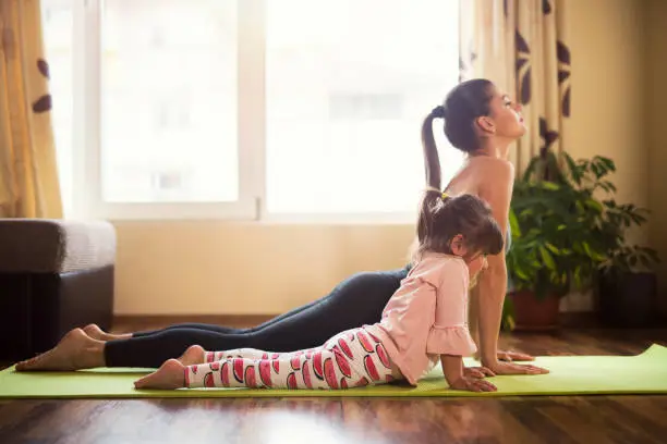 Photo of You're doing it like mommy now, Full length shot of a mother and daughter doing yoga together