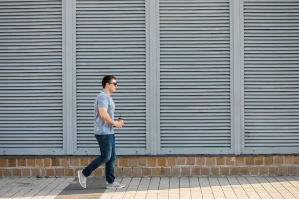 istock A young man drinks coffee in the city and walks outside. 1142610782