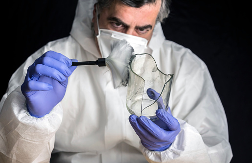 Expert Police get fingerprints from a broken glass bottle in Criminalistic Lab, conceptual image