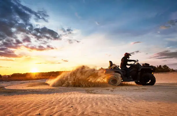 Racing powerful quad bike on the difficult sand in the summer.