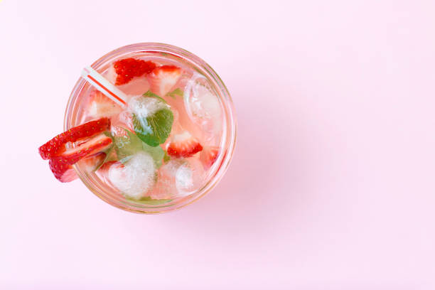 istock Cold summer drink with ice and strawberries on a pink background, top view 1142616877