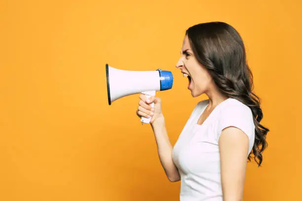 Vibrant orange background with an angry girl next to it who is loudly screaming and using a megaphone for it.