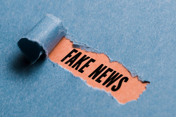 torn paper revealing the phrase "Fake News" stock photo