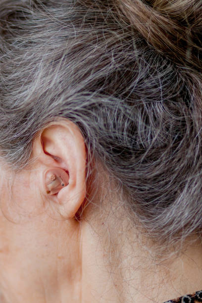 istock closeup senior woman inserting hearing aid in her ears 1142625258