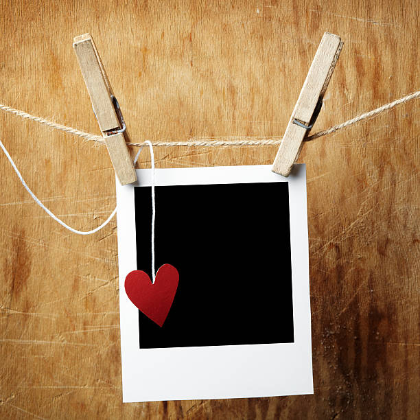 istock Blank picture frame and small heart hanging on clothesline 114262554