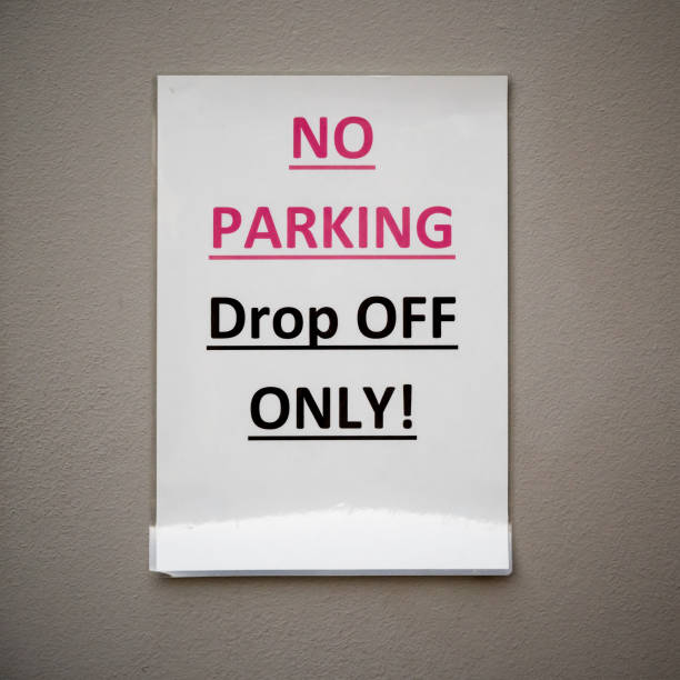 istock Laminated paper sign saying NO PARKING Drop OFF ONLY! on beige wall 1142630295