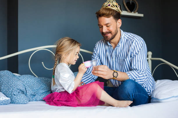 adorable niña está teniendo té fiesta con su padre - tea party little girls teapot child fotografías e imágenes de stock