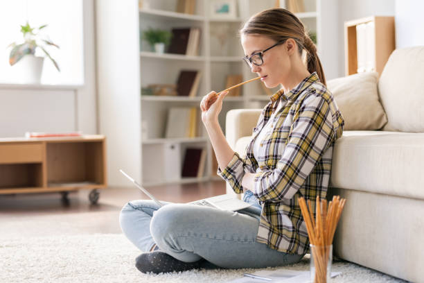 Thoughtful girl reading article on laptop