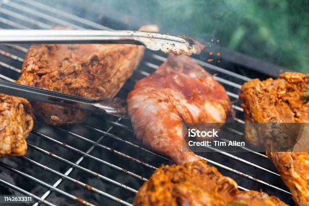 Home Chef Turning Chicken Over To Cook Other Side On Barbecue Stock Photo - Download Image Now