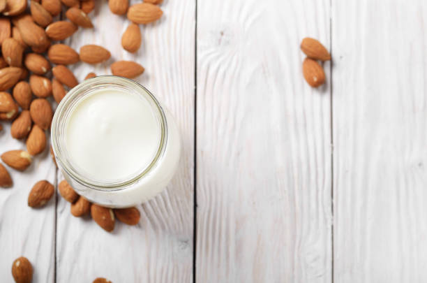 istock Milk or yogurt in mason jar on white wooden table with almonds aside flat lay view 1142634273