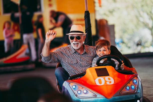 Grandfather and grandson amusement park fun Grandfather and grandson having fun and spending good quality time together in amusement park. They enjoying and smiling while driving bumper car together. rollercoaster photos stock pictures, royalty-free photos & images