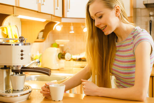 istock Woman in kitchen making coffee from machine 1142643715