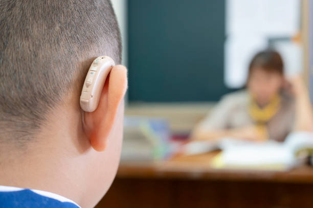 Students who wear hearing aids to increase hearing efficiency. Students who wear hearing aids to increase hearing efficiency. Helps to be able to learn as much as a friend. The background is a teacher who is talking to him. deafness photos stock pictures, royalty-free photos & images