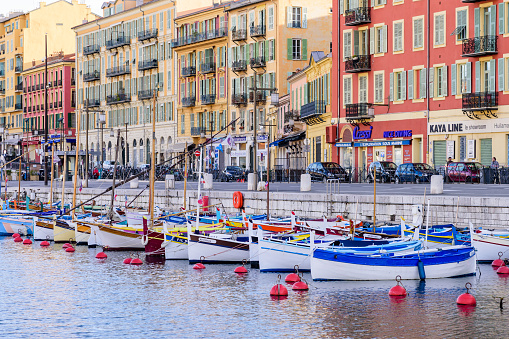 Nice, Cote d'azur, France - March 8, 2018: port with traditional fishing boats in the center of Nice city and colorful buildings with bright facades in the background