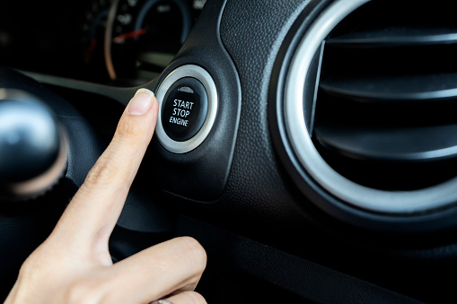 Using the push button to start and stop engine, The woman's finger is pressing down. Comfort in driving a car is something everyone wants.