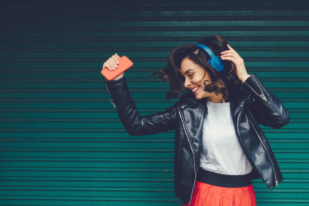 Gen Z girl enjoying disco music Beautiful woman dancing to the music against coloured wall music culture stock pictures, royalty-free photos & images