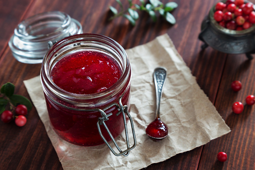 Horizontal photo of Jar of berry jam with a spoon on wooden table