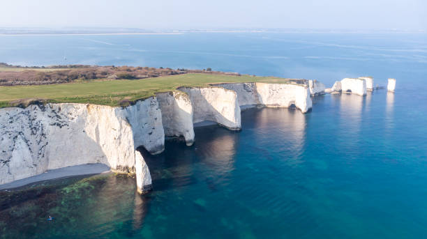 An aerial view of the Old Harry Rocks along the Jurassic coast with crystal clear water and white cliffs under a hazy sky An aerial view of the Old Harry Rocks along the Jurassic coast with crystal clear water and white cliffs under a hazy sky jurassic coast world heritage site stock pictures, royalty-free photos & images