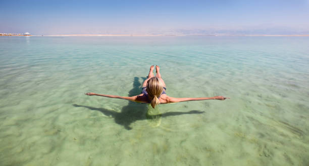 mujer rubia flotando en las aguas turquesas del mar muerto - dead sea fotografías e imágenes de stock