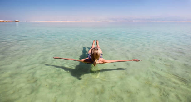 Blonde woman floating in the turquoise waters of the Dead Sea stock photo