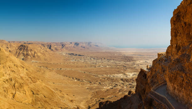 istock Panoramic view of the valley surrounding Masada and its cliffside walkways 1142660494